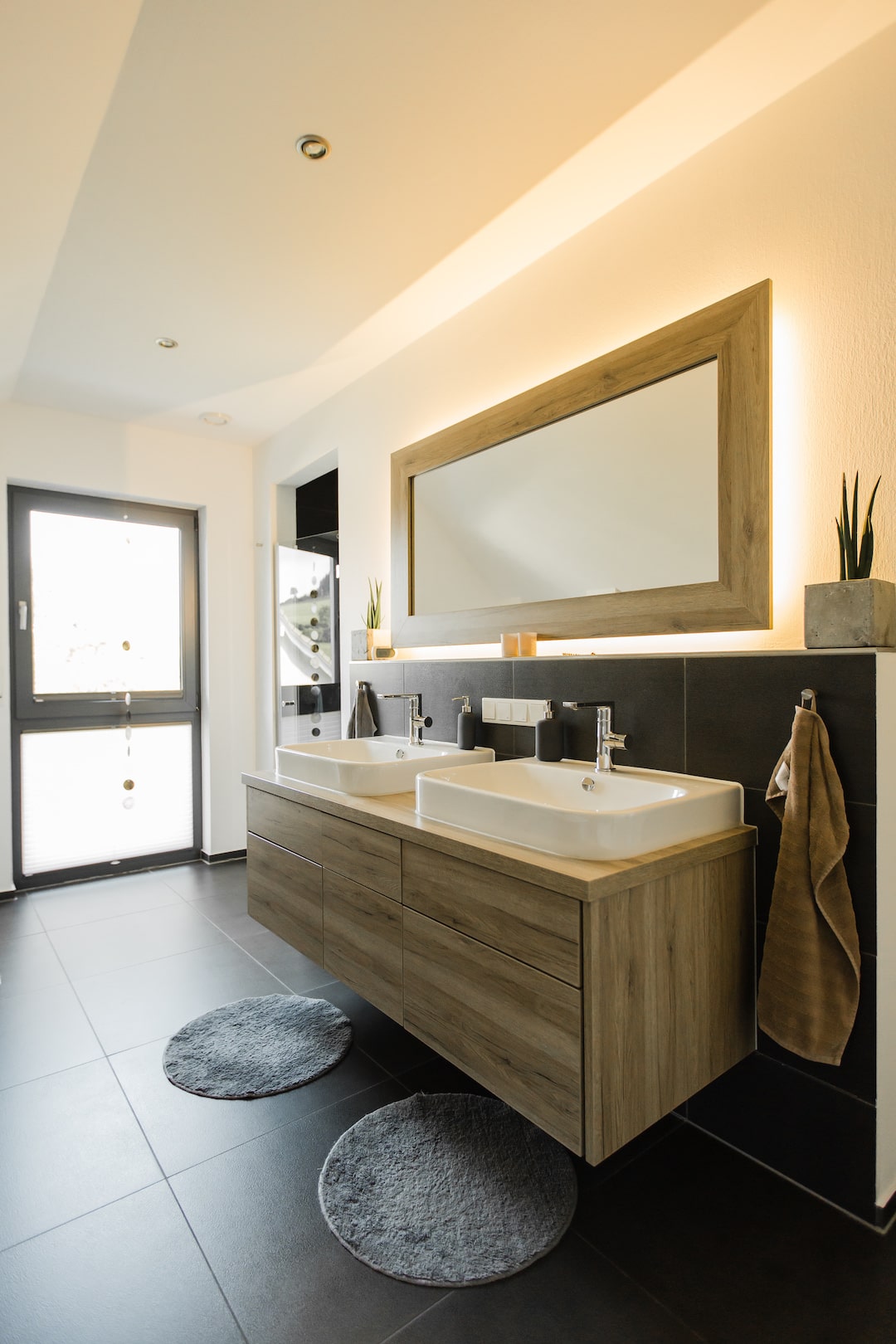 Modernes Badezimmer im Partner-Haus Fertighaus – Doppelwaschtisch mit Holzoptik und stilvoller Beleuchtung